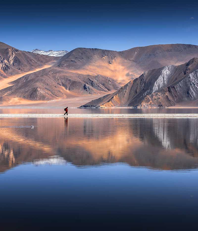 morador local caminhando com reflexo na água em Ladakh
