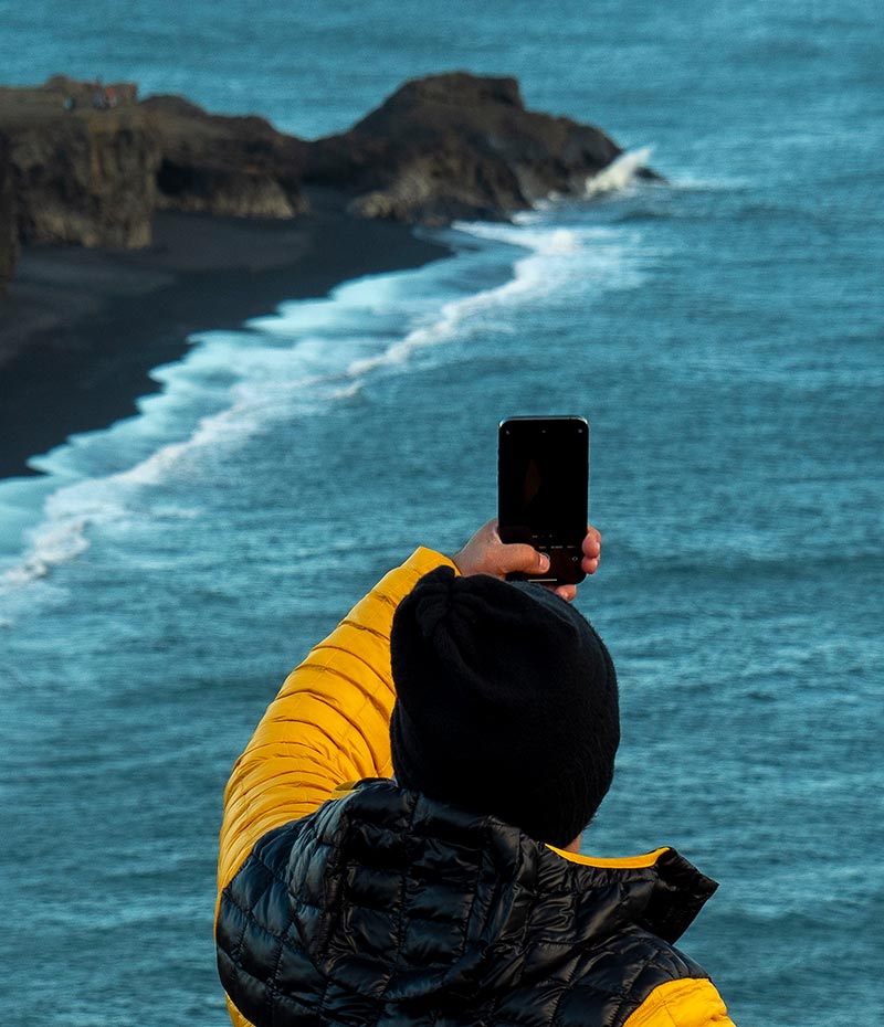 turista fotografando paisagem na costa da Islândia