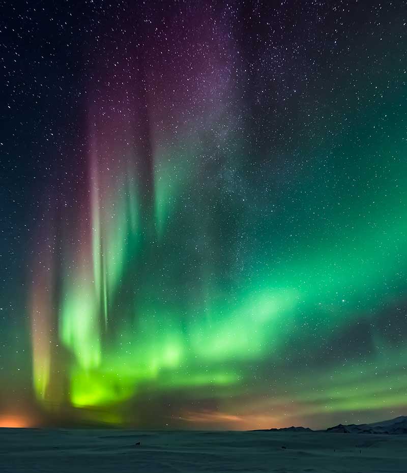 aurora boreal iluminando o céu noturno na Islândia