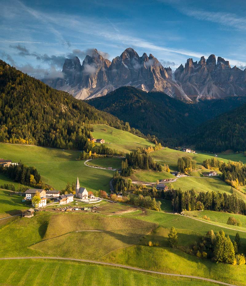 Paisagem das Dolomitas nos Alpes Italianos, com montanhas, vales verdes e pequenas vilas alpinas