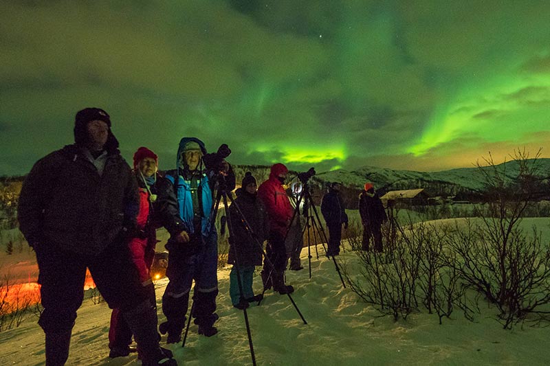 Grupo de viajantes fotografando a aurora boreal na Noruega